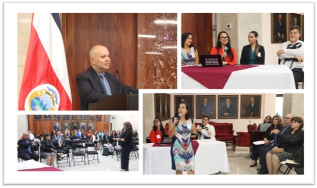 Fotografía superior izquierda: Una persona se encuentra en un podio o atril realizando una intervención ante el público. A un lado se aprecia una bandera de Costa Rica. El fondo está compuesto por paneles de madera y una pared de mármol o piedra pulida.  Fotografía superior derecha: Cuatro personas están sentadas detrás de una mesa cubierta con manteles blancos y vino. Sobre la mesa hay una computadora portátil. Parecen participar en un panel o mesa principal del evento.  Fotografía inferior izquierda: Vista general del salón. Varias personas permanecen sentadas en filas de sillas escuchando una presentación. Al frente se observa una persona de pie dirigiéndose a la audiencia.  Fotografía inferior derecha: Una persona sostiene un micrófono y realiza una exposición o presentación. Detrás se encuentran otras personas sentadas en una mesa principal. En la pared del fondo se distinguen varios retratos enmarcados, lo que sugiere un espacio institucional o histórico.